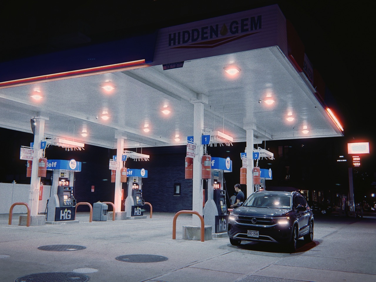 Night gas station with red halation glow around bright lights